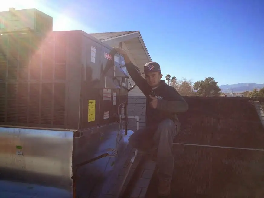 HVAC technician performing AC Tune-Up on a rooftop unit in Watertown